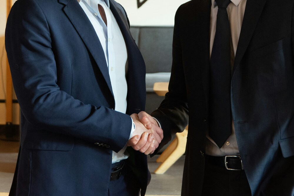 Seller and buyer shaking hands after agreeing terms of a business sale.